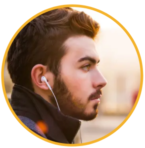 A young professional with short dark hair and a trimmed beard listens to audio through white earbuds while looking ahead with focus during a sunrise commute. The soft golden light highlights his face as he learns workplace and banking skills through the CFTEA Global Workplace Skills Audio Library, supporting his confidence and career growth.