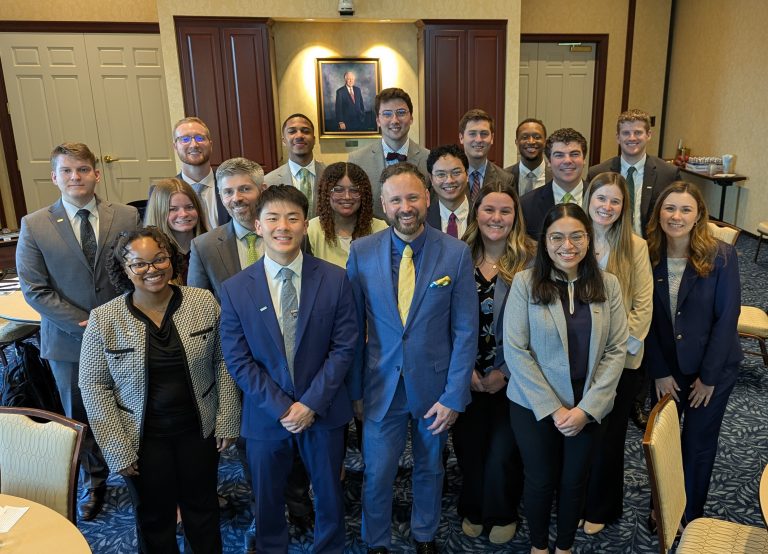 CFTEA Executive Director, Andrew Lederer with group of young banking professionals and mentors standing together in a conference room during a leadership training program, dressed in business attire and smiling for a group photo.